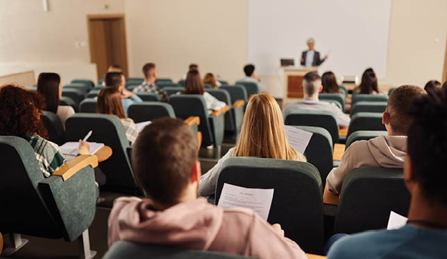 Image d'une classe d'étudiants et édutiantes écoutant un enseignant.