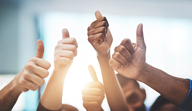 Cropped shot of a team of colleagues showing thumbs up at work