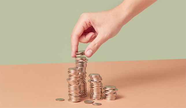 A hand stacking coins.